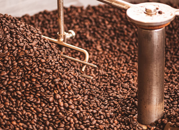 Koffiebonen roosteren in een professionele oude koffiebranderij of koffiebranderij, close-up - Foto, afbeelding
