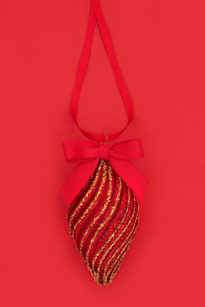 Dekoracja choinki w kolorze czerwonym i złotym wiszące na wstążce z łukiem. Tradycyjny symbol świątecznego święta Bożego Narodzenia. - Zdjęcie, obraz