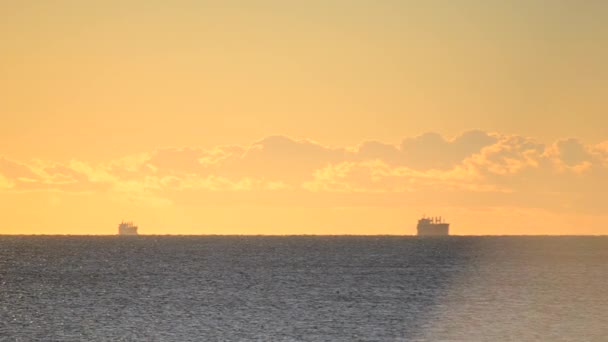 Denizdeki ufuk çizgisinde tanker tankerlerinin silueti ve gün batımında sarı mavi gökyüzünde hızlı hareket eden bulutlar. Deniz manzarası, deniz manzarası. Ulaşım. Doğal arkaplan - Video, Çekim