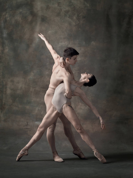 Young man and woman, ballet dancers performing isolated over dark green vintage background. Passion and support. Contemporary ballet. Concept of classic dance, artist, beauty. Copy space for ad - Foto, Bild