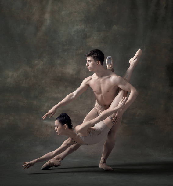 Young man and woman, ballet dancers performing isolated over dark green vintage background. Beauty of dance. Contemporary ballet. Concept of classic dance, artist, beauty. Copy space for ad - Photo, Image