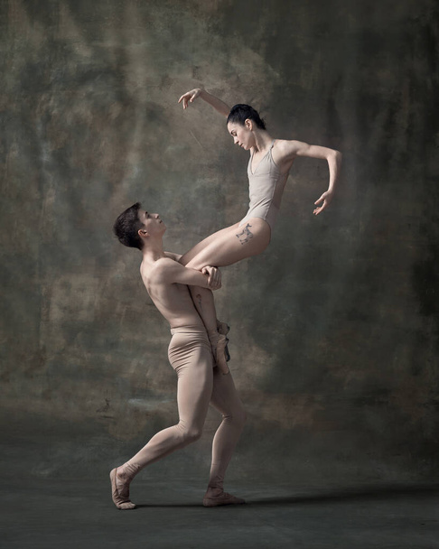 Jovem homem e mulher, dançarinos de balé realizando isolado sobre fundo verde escuro vintage. Posição difícil. Ballet contemporâneo. Conceito de dança clássica, artista, beleza. Espaço de cópia para anúncio - Foto, Imagem