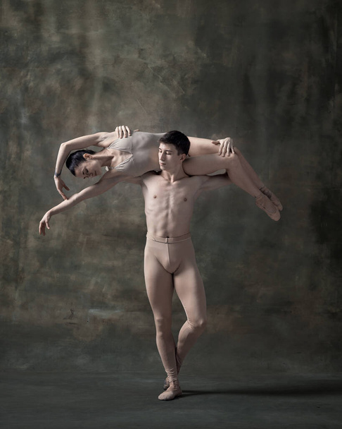 Young man and woman, ballet dancers performing isolated over dark green vintage background. Sensuality and elegance. Contemporary ballet. Concept of classic dance, artist, beauty. Copy space for ad - Foto, Imagem