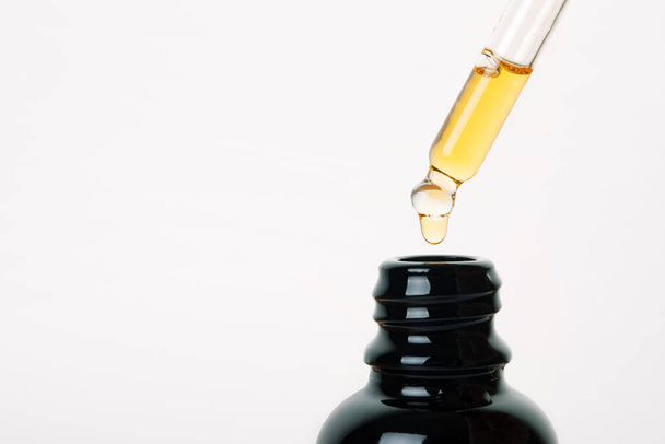 Крапелька з олією, що використовується для медичних цілей, CBD олія зблизька над сірим фоном - Фото, зображення