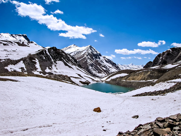 Montagnes enneigées avec un petit lac et nuages blancs en fond de ciel bleu sur le chemin de Leh. - Photo, image