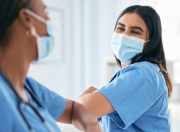 Covid, women and doctors elbow greeting in surgical mask at hospital or clinic during the pandemic. Teamwork, healthcare worker and medical professional with protection from virus for doctor or nurse. - Photo, Image