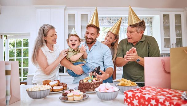 Baby, birthday party and family celebration at a kid event with mother, father and friends. Young child and parents celebrate event with food clapping for a happy boy in a family home kitchen. - Photo, image