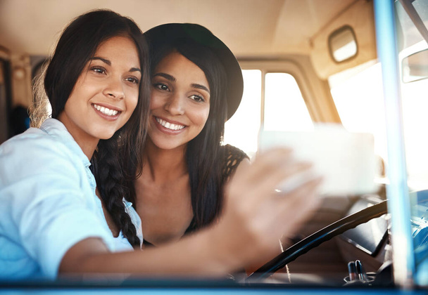 Its not a road trip until you take a selfie. two happy friends taking selfies with a mobile phone on a roadtrip - Foto, immagini