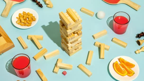 友人と楽しさとエンターテイメントとレジャーのためのJengaボードゲーム。テーブルの上に食べ物や飲み物とキューブの木製の塔. - 映像、動画