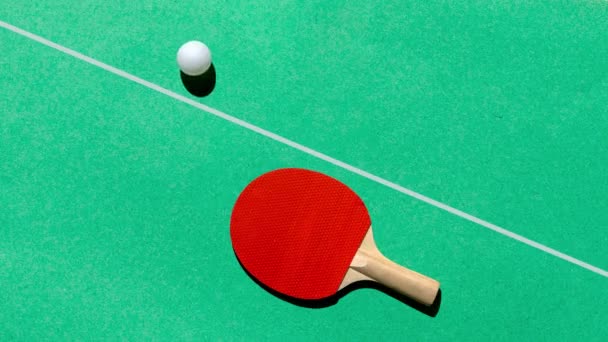 Vrolijke ping pong op een groene tafel, een rode racket en een witte bal rolt. Video stop motion minimaal concept. - Video