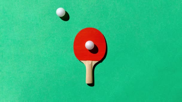 Egy piros ping-pong asztalitenisz ütő a zöld asztalon, és a fehér golyók mozgása, mint egy minta. Minimális koncepció a sport, a szórakozás és a kikapcsolódás. Kiváló minőségű FullHD felvételek - Felvétel, videó