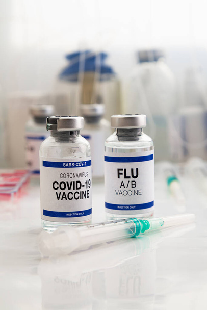 Frascos de vacuna contra el Coronavirus y vacuna antigripal para la vacunación de recuerdo de nuevas variantes del virus Sars-cov-2 y la gripe A. Viales de vacuna contra la gripe A-B y Covid-19 para la inyección de refuerzo para el virus de la influenza y el omicrón - Foto, Imagen