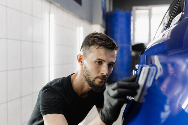 Hand applying of nano ceramic protective coat to protect car from scratches. Process of apply ceramic layer on body car using sponge in detailing auto service - Fotografie, Obrázek