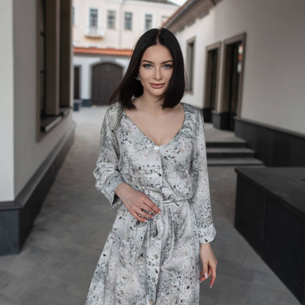 Moody beautiful girl Caucasian model with a bob haircut in a stylish vintage dress in a floral pattern walks in the city - Foto, imagen