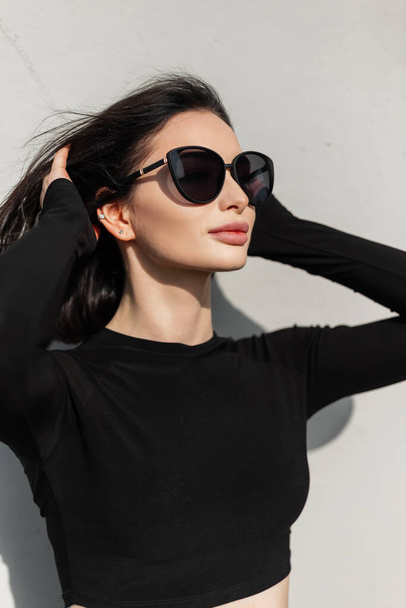 ストリート上のファッション黒の服で流行のサングラスを持つ美しい女性の都市女性の肖像画 - 写真・画像