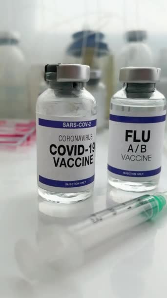 コロナウイルスワクチンボトルとインフルエンザショットワクチンは、新型のSar-cov-2ウイルスおよびインフルエンザAに対するブースターワクチン接種を可能にする。マイクロウイルスとインフルエンザウイルスのためのブースターショットのためのインフルエンザA-BとCovid-19ワクチンのバイアル - 映像、動画