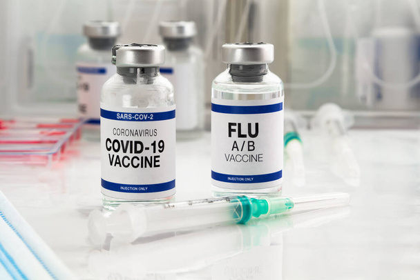 Φιάλες εµβολίου του Coronavirus και εµβόλιο για αναµνηστικό εµβολιασµό για νέες παραλλαγές του ιού Sars-cov-2 και της γρίπης A. Φιαλίδια εμβολίου Flu A- B και Covid- 19 για αναμνηστική ένεση για τον ιό omicron και την γρίπη - Φωτογραφία, εικόνα