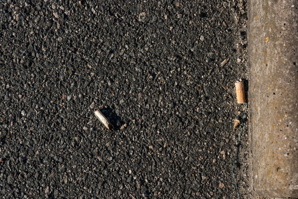 Gotemburgo, Suecia - 24 de junio de 2021: Dos colillas de cigarrillos sobre asfalto. - Foto, Imagen