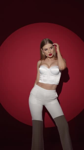 Sexy chica en un traje blanco sobre un fondo rojo - Imágenes, Vídeo