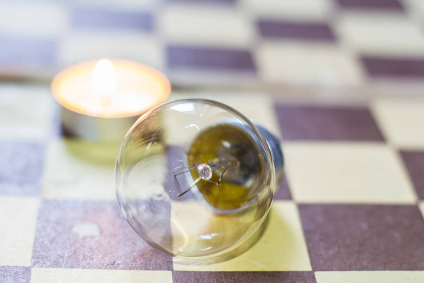 Queimar vela e lâmpada em um tabuleiro de xadrez. Blackout devido à guerra na Ucrânia - Foto, Imagem