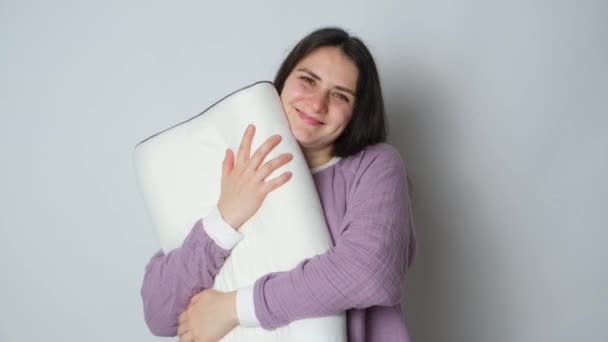 Mulher bonita morena em musselina pijama roxo roupas de dormir abraça o travesseiro ortopédico - Filmagem, Vídeo