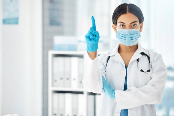 Woman, pointing doctor and covid face mask in hospital, clinic or wellness pharmacy for global virus stop, compliance or rules. Portrait, healthcare worker or medical employee with advertising space. - Фото, изображение