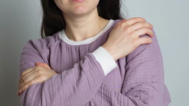 Eine brünette Frau im lila warmen Musselin-Pyjama umarmt sich und genießt den Komfort der Schlafkleidung. - Filmmaterial, Video