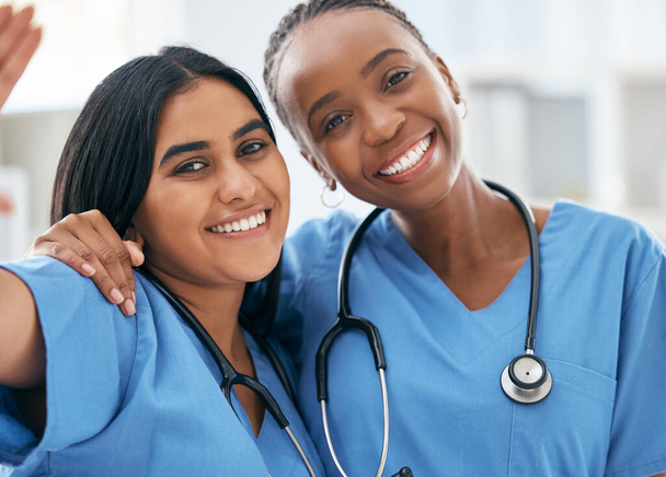 Doctors, selfie and women friends at hospital smile for photograph together with stethoscope. Happy, healthcare and interracial friendship picture of professional cardiology workers on break - Photo, Image