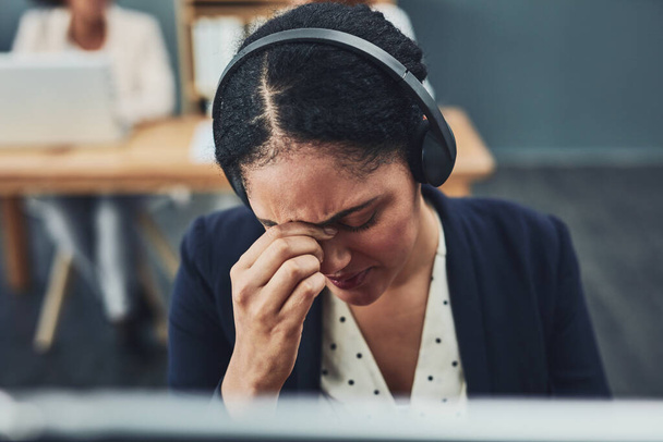 Esto se está poniendo demasiado. una joven mujer de negocios estresada trabajando en su computadora mientras escucha a un cliente por teléfono dentro de la oficina en el trabajo - Foto, imagen