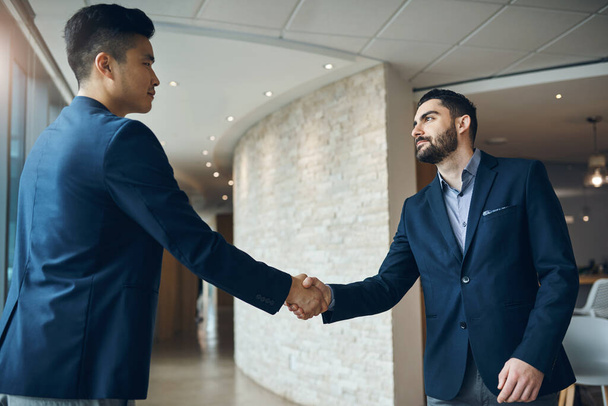 競技者はこのパートナーシップに反対する機会はありません。2人の若いビジネスマンが現代のオフィスで握手をし - 写真・画像