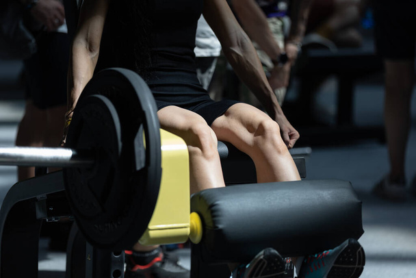 Девушка делает упражнения в тренажерном зале: Расширения ноги тренировки на тренажере
. - Фото, изображение