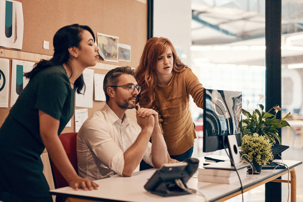 Poner al equipo en una tarea de diseño. un grupo de empresarios que utilizan un ordenador juntos en una oficina moderna - Foto, Imagen