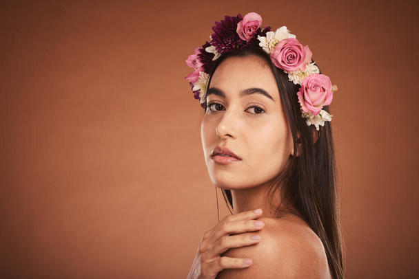 Makeup, beauty and woman with floral crown on head to model for cosmetics, beauty products and fashion. Creative, hair and artistic portrait of girl with flower headband on brown background studio. - Fotó, kép