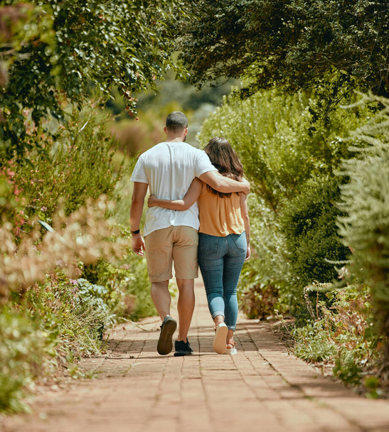 夏には、自然の中で平和、リラックス、絆のためのパス上の抱擁、歩くとカップル。春に公園や庭で愛情を込めて、抱きかかえ、愛を持って歩く男と女の背中. - 写真・画像
