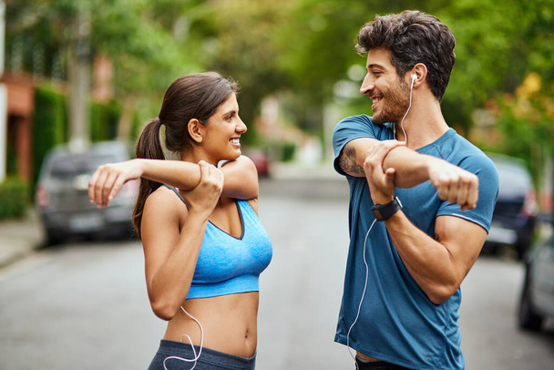 First we start with a good few stretches. a sporty young couple stretching while exercising together outdoors - Photo, image
