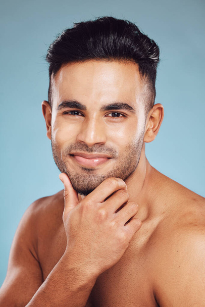 Skincare, beauty and a portrait of man, topless touching beard with healthy skin and natural facial glow and smile on face in India. Male body care, health and model in studio with blue background - Photo, Image