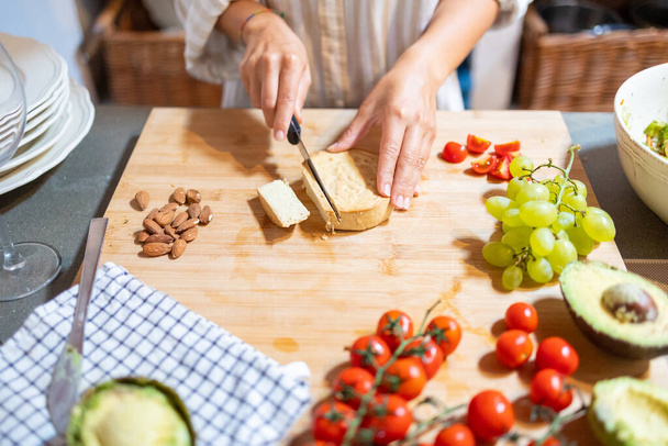 Female hands cutting slices of almond vegan cheese for breakfast - Fotografie, Obrázek