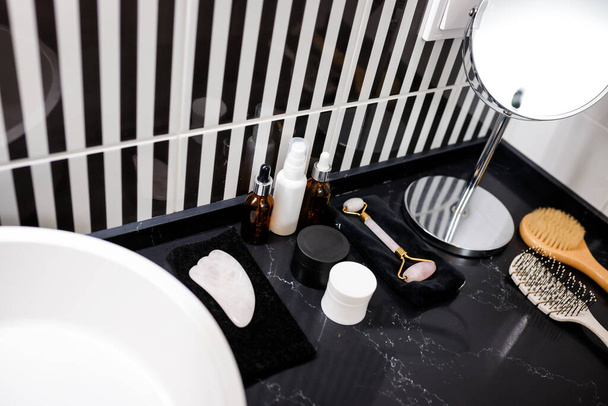 Різні засоби по догляду за тілом і шкірою на столі на тлі темного фону в домашній ванній
 - Фото, зображення
