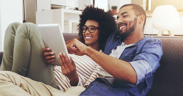 Prohlížení internetu společně. veselý mladý pár sedící na gauči při prohlížení digitálního tabletu spolu v obývacím pokoji - Fotografie, Obrázek