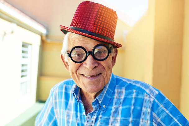 I can actually see through these glasses. a carefree elderly man wearing funky glasses and a hat while posing for the camera inside a building - 写真・画像