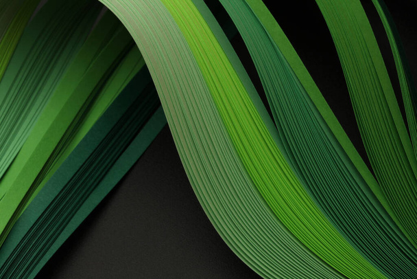 Green neon color strip wave paper on black. Abstract texture copy space background. - Foto, afbeelding