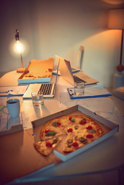 Petiscos saborosos para te ver durante a noite. Fotografia de vida morta de pizza em uma mesa em um escritório - Foto, Imagem