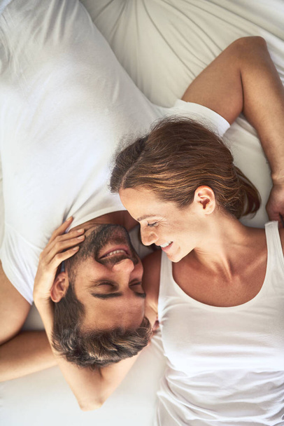 A tiéd vagyok, az enyém vagy. Nagy látószögű felvétel egy boldog fiatal párról, akik otthon pihennek az ágyban. - Fotó, kép