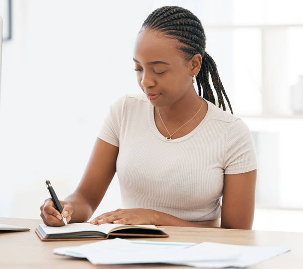 Notebook, working and black woman writing notes in office, sitting at desk. Ideas, vision and businesswoman with pen in hand to write, jot and taking notes in business meeting in book or work diary. - Foto, Imagem
