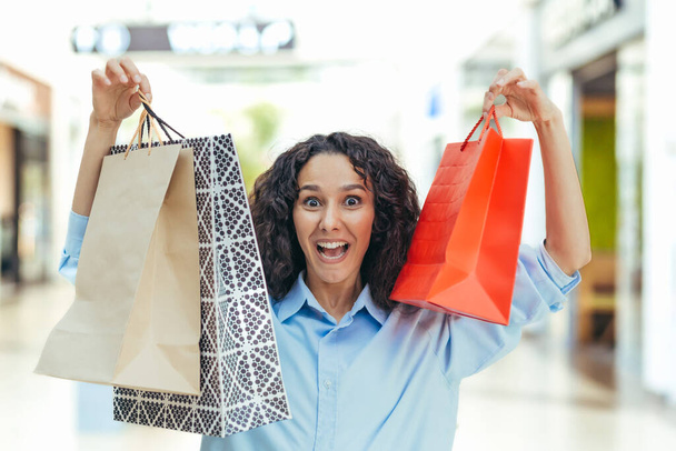 Portrait of a happy woman shopper, Hispanic woman in a supermarket with colorful bags is happy and looking at the camera, inside a large clothing store - Foto, immagini
