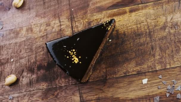 Banánový čokoládový dort se zlatým prachem na dřevěném podnosu s dekoracemi. - Záběry, video
