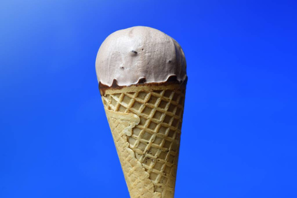 Cono de helado de chocolate sobre fondo azul - Foto, Imagen