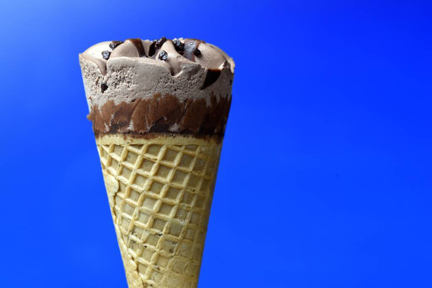 Cono de helado de chocolate sobre fondo azul - Foto, imagen