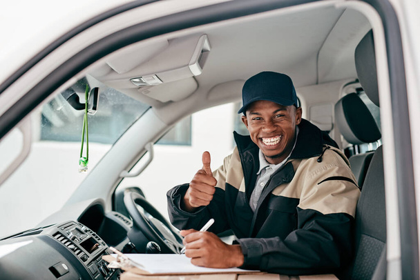 Great service is our promise to you. Portrait of a courier showing thumbs up while sitting in a delivery van - 写真・画像