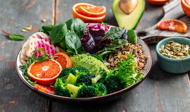 Vegan, detox Buddha bowl with vegetables, avocado, blood orange, broccoli, watermelon radish, spinach, quinoa, pumpkin seeds. Balanced food Delicious detox diet. Top view. - Photo, Image